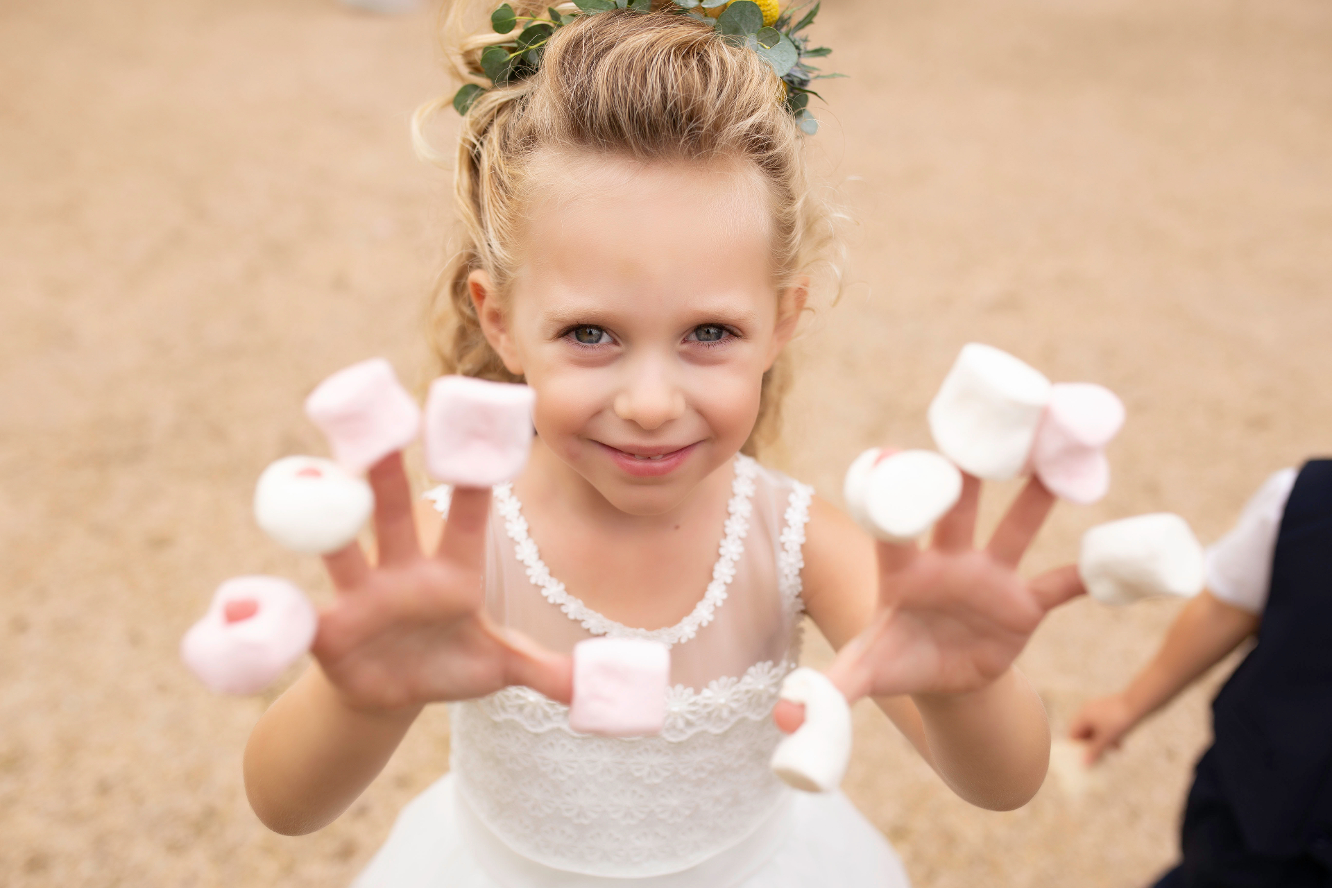 Enfant souriante au mariage, marshmallows au bout des doigts